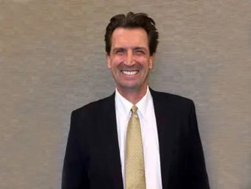 Dr. Stephen Forrest, DDS, of Des Moines Cosmetic Dentistry Center, in a dark suit.